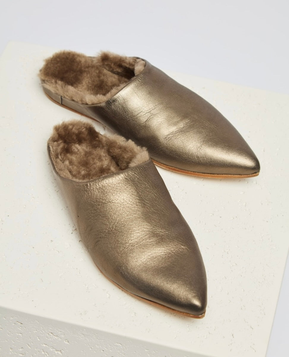 Metallic gold, pointed-toe slippers with a soft, furry interior lining and a smooth, leather-like exterior.